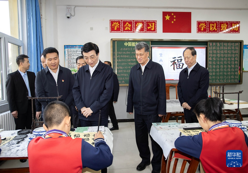 10月21日至24日，中共中央政治局常委、全国政协主席王沪宁在新疆和田、喀什调研。这是23日上午，王沪宁在和田市第十二小学观看书法课堂，了解学校开展民族团结教育情况。新华社记者 李涛 摄.png